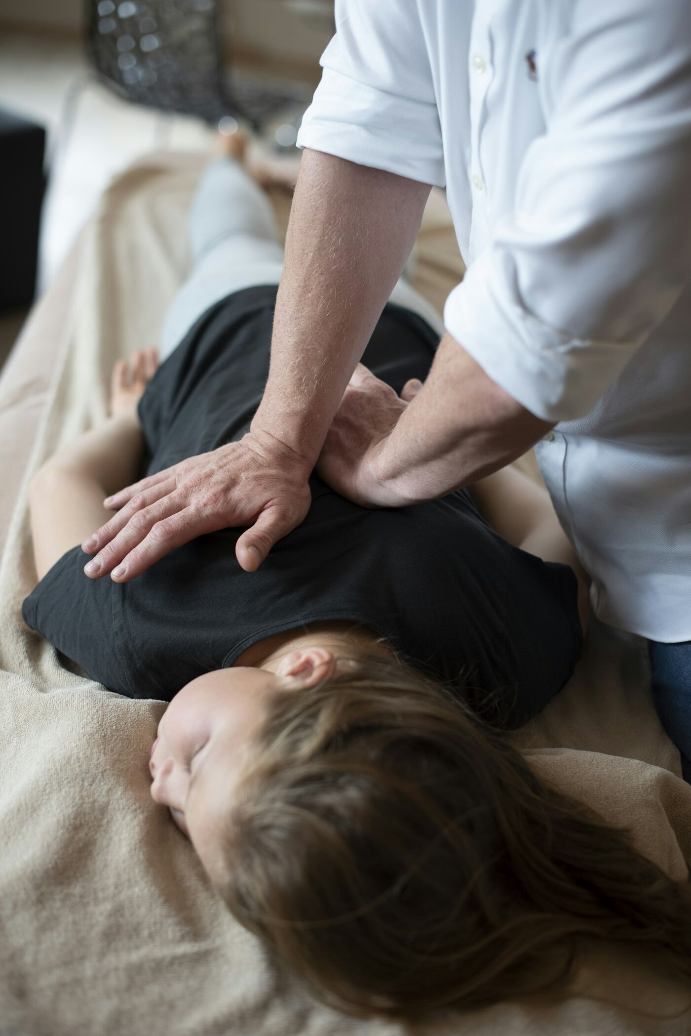 A physiotherapist pressing gently on a patient's lower back