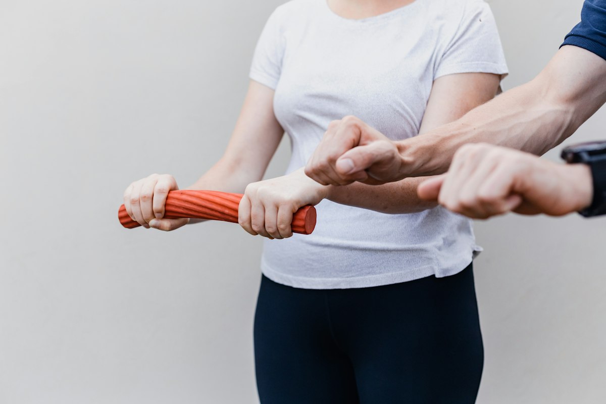 A patient squeezing a grip bar while the physiotherapist supports her arm