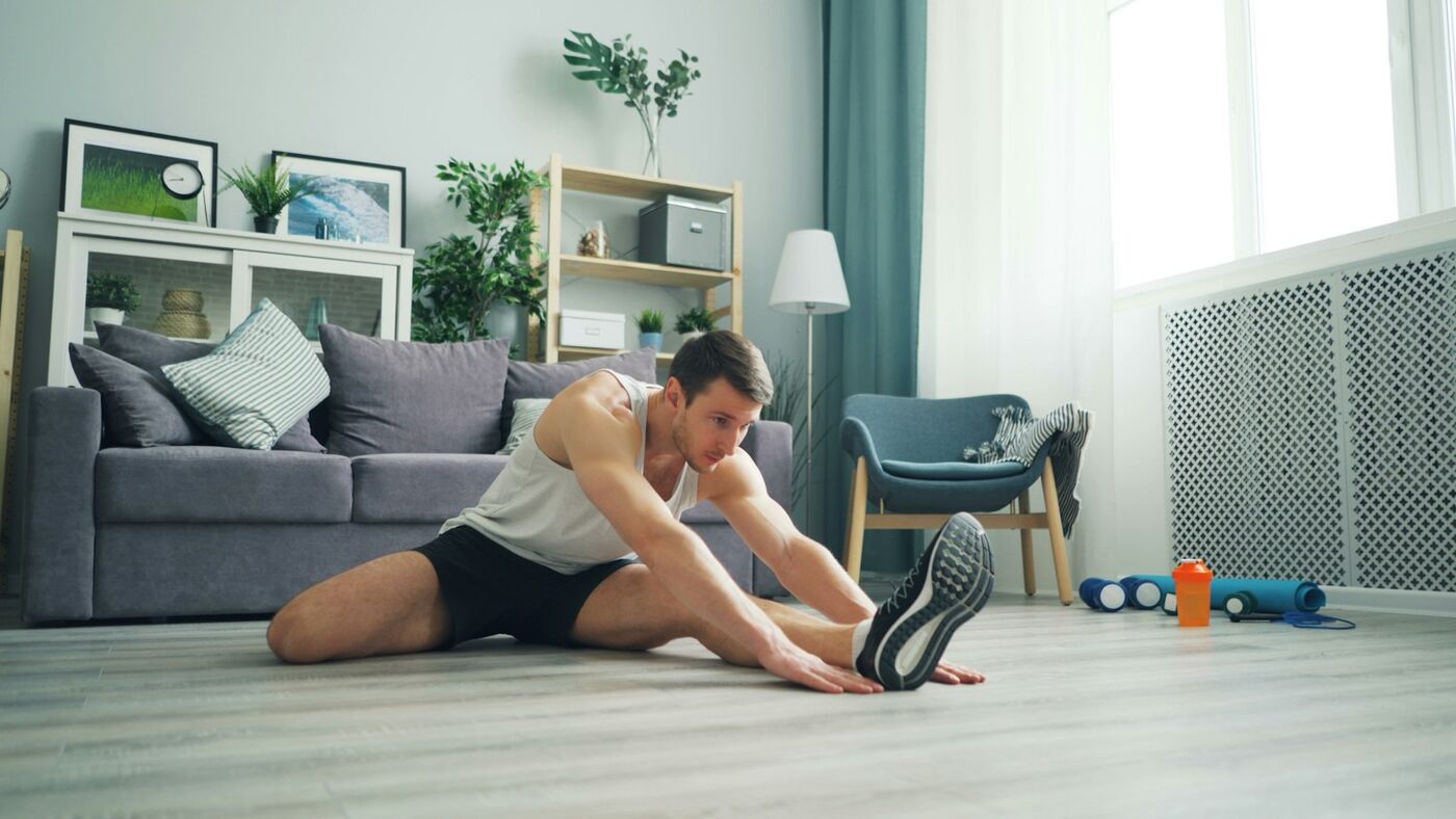 A woman doing a stretch on a mat in her living room