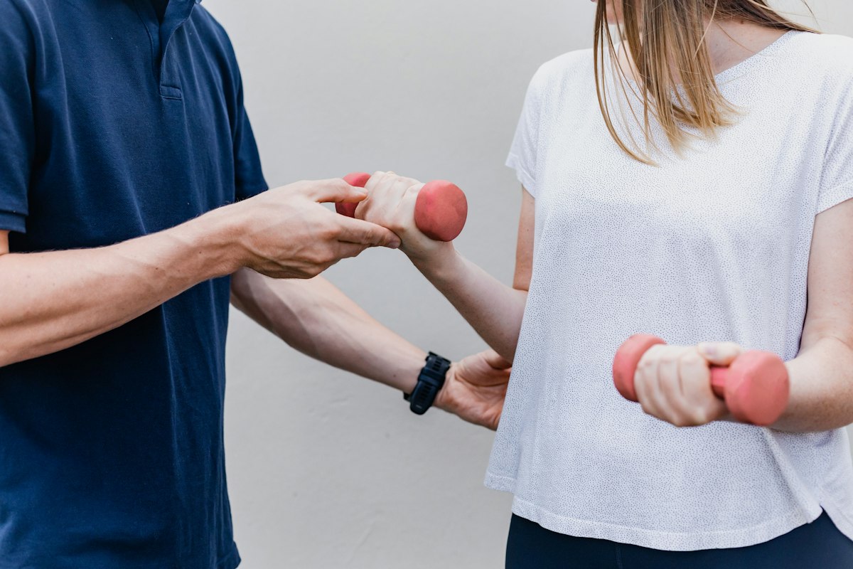 A physiotherapist showing a patient an exercise with light dumbbells