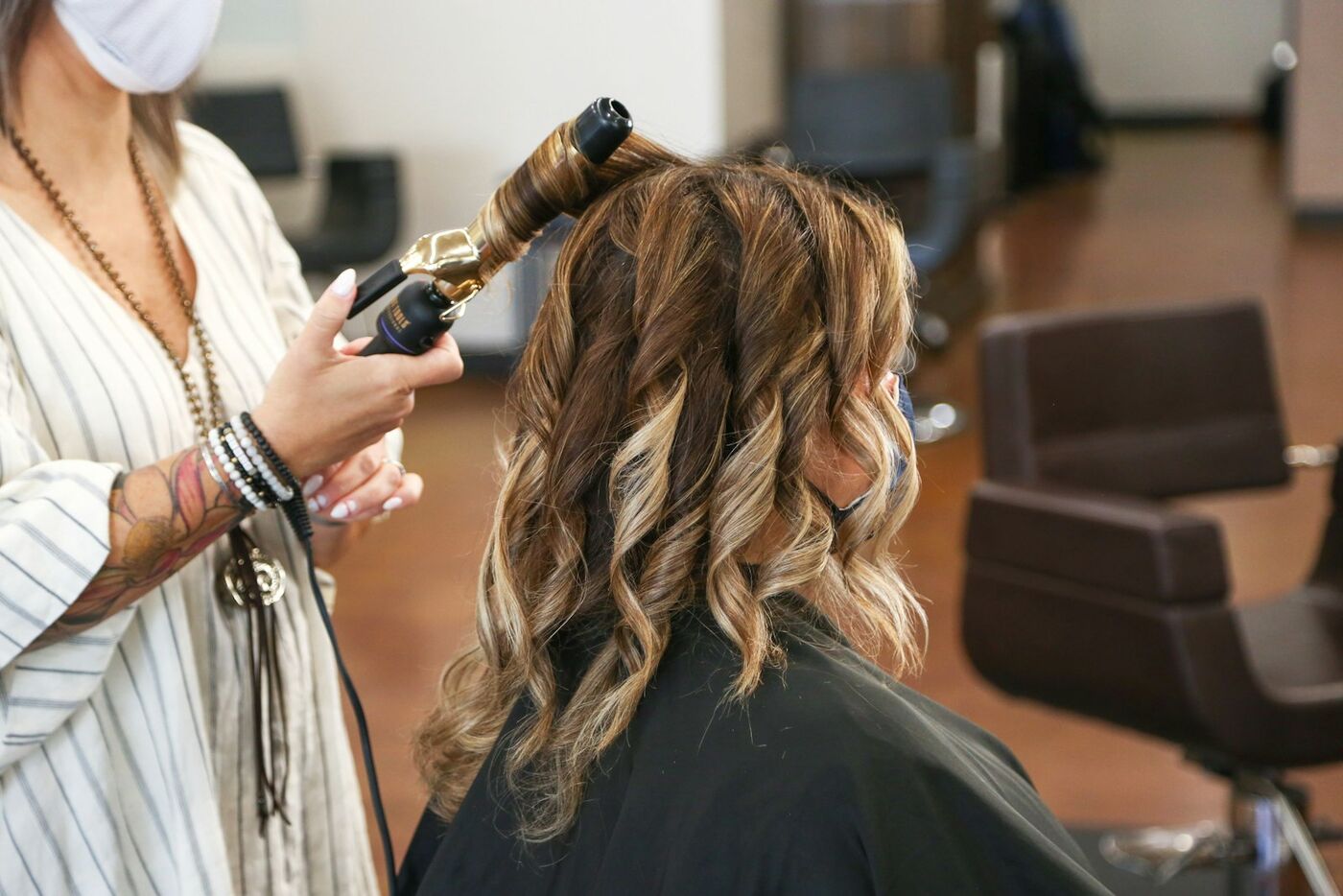 A stylist curling long hair with a wand