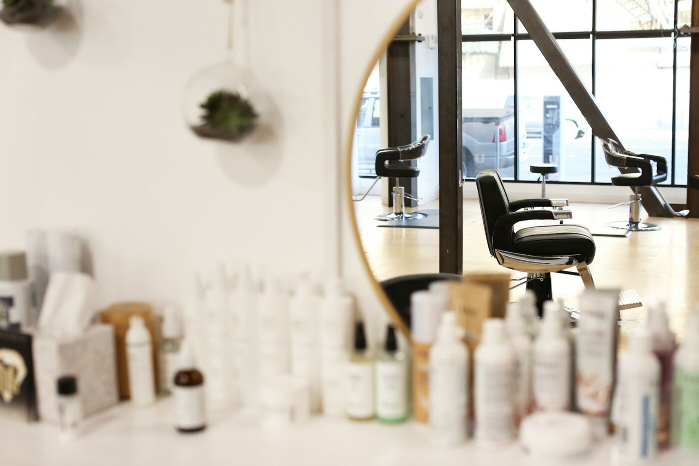 Hair care bottles lined up on a shelf by a round mirror