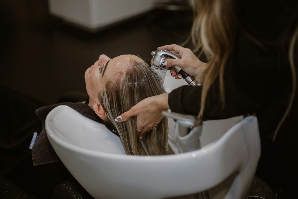 A client having her hair washed at the basin