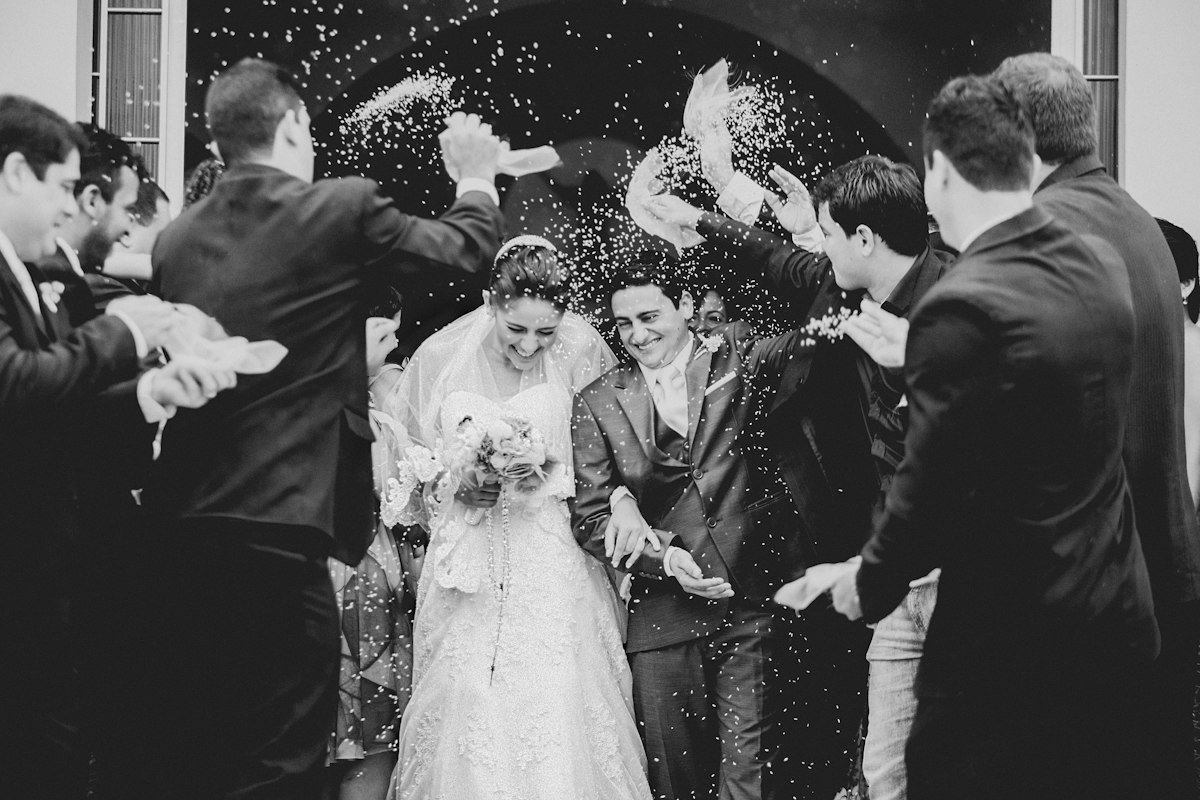 Black and white photo of guests throwing confetti over the newlyweds