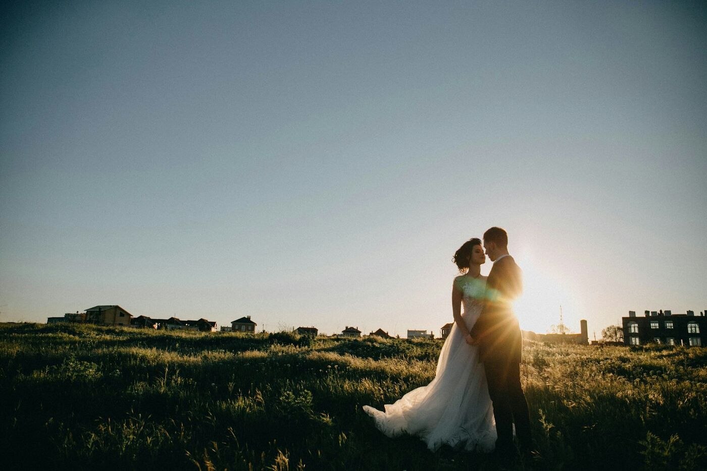 A couple holding each other in a field at sunset